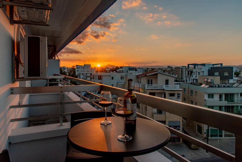 a balcony with a table and two glasses of wine at TelMar Sky View in Larnaca