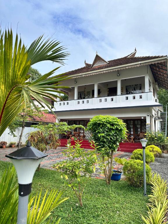a large white building with a palm tree in front of it at 4elementis beach homestay in Mararikulam