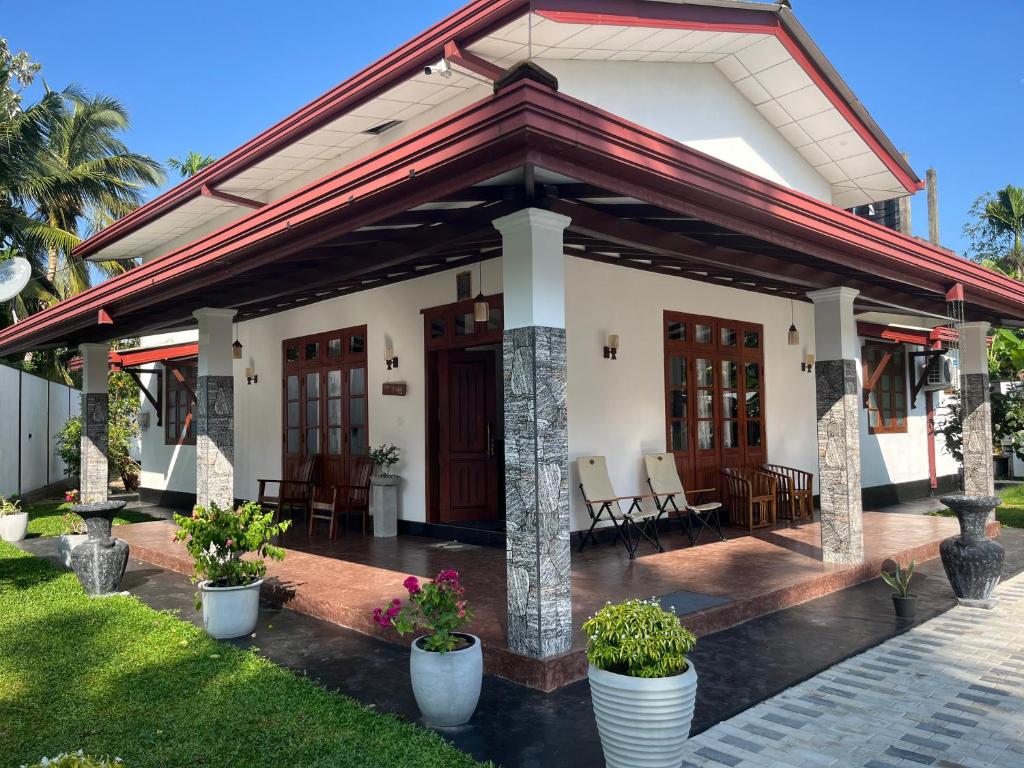 a house with a porch with chairs and plants at Villa J-95 in Galle