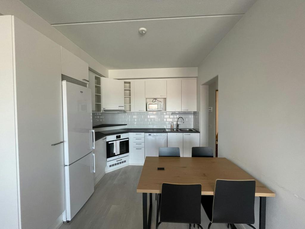 a kitchen with a wooden table and white appliances at Central Apartment for 4 with Sauna in Seinäjoki