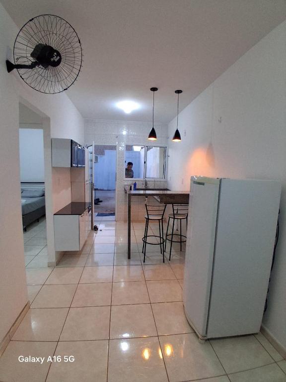 a kitchen with a refrigerator and a table with chairs at Casa de férias Pôr do Sol 2 in Presidente Epitácio