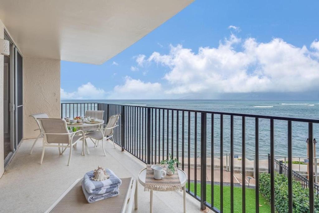 a balcony with a table and chairs and the ocean at Hololani B204 · HL B204 Beachy Chic Updated OceanFront 2BD in Kahana
