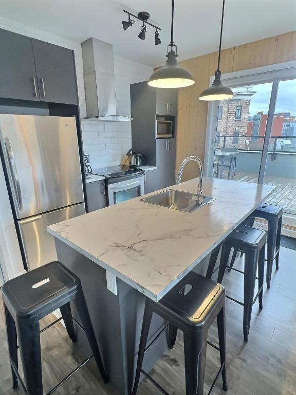 a kitchen with a large kitchen island with stools at Chez Temporel - Condo urbain in Quebec City