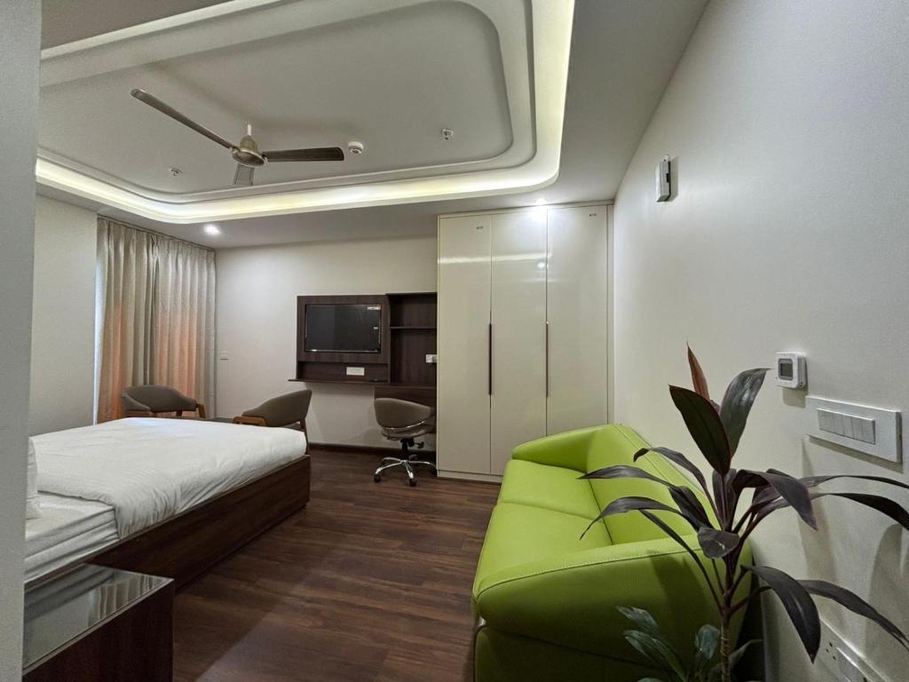 Una habitación de hotel con una cama, un sofá y un televisor. en QuickIn Stayz managed by The AIKaya Hotels, en Gurgaon