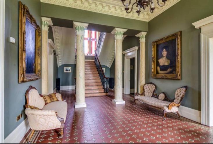 a living room with chairs and a staircase in a house at Ballynacree House and Cottages in Balnamore