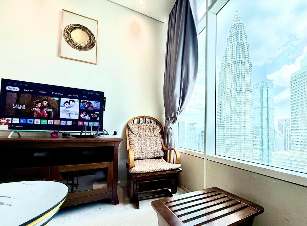 The Apartment Sky Suites KLCC by Ayman في كوالالمبور: غرفة معيشة مع مكتب ونافذة كبيرة