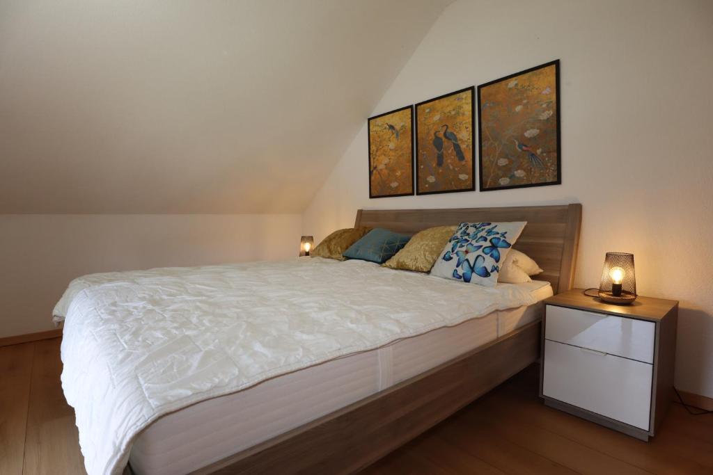 a bedroom with a large bed and two paintings on the wall at Ferienwohnung Freizeitglück nahe Europapark - Mein Schwarzwaldhäusle in Kappel-Grafenhausen