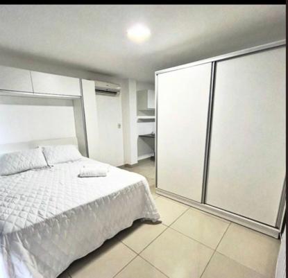 a bedroom with a white bed and a sliding glass door at Aruanda Beach - Praia de Tambaú in João Pessoa