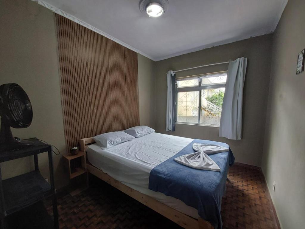 a bedroom with a bed with a blue blanket and a window at Hostel Pantanal Em Florianópolis in Florianópolis