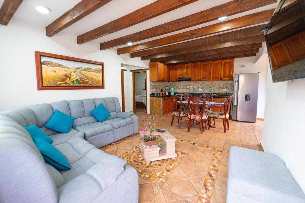 a living room with a blue couch and a kitchen at Apartamento Madeiro in Villa de Leyva
