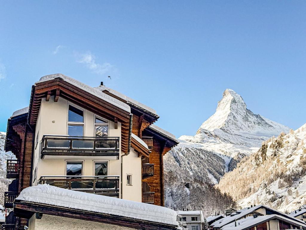 un edificio con una montaña cubierta de nieve en el fondo en Hotel Capricorn, en Zermatt
