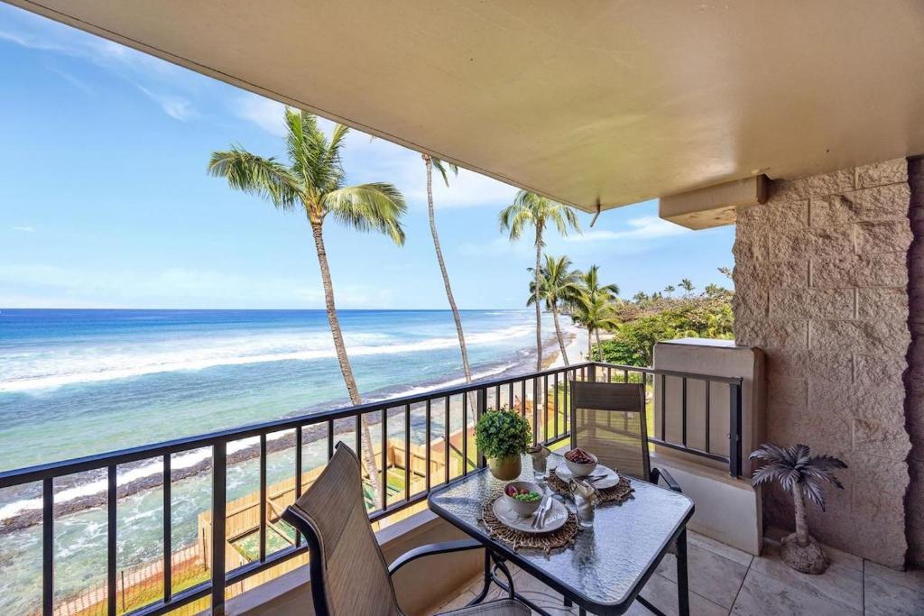 a table on a balcony with a view of the beach at Paki Maui 301 · Direct Oceanfront Views Remodeled 2BD Condo in Kahana