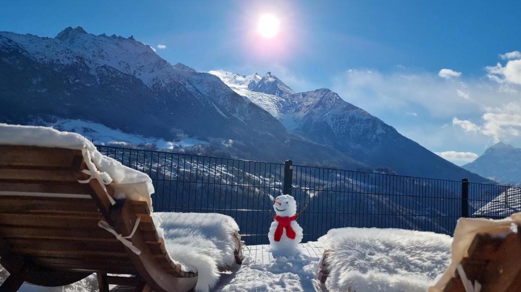 a snow covered bench and a teddy bear in the snow at Mattertal Lodge in Embd