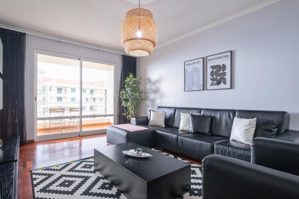 a living room with a black leather couch and a table at Piornais by Homie in Panasqueira