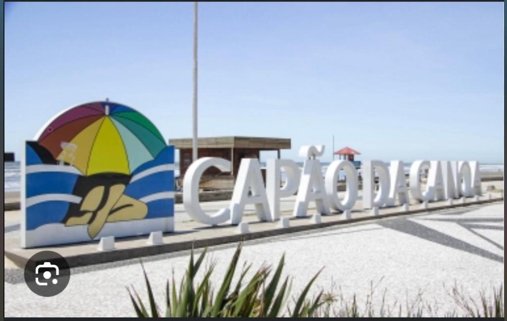a sign for a beach with an umbrella at Casa pertinho do mar in Capão da Canoa