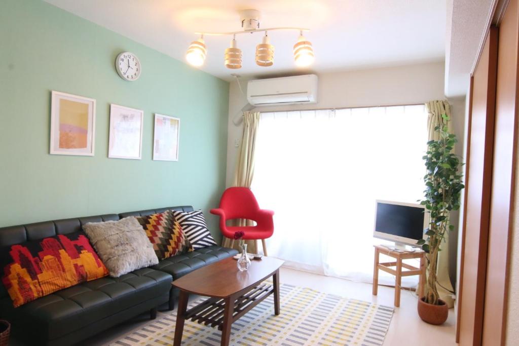 un soggiorno con un divano nero e una sedia rossa di Pine Hills Minoshima - Vacation STAY 12181 a Sumiyoshi