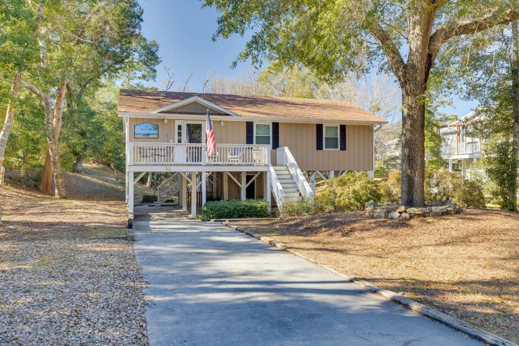 a house with a porch and a flag on a sidewalk at Lovely Emerald Isle Home, Walk to Beach! in Emerald Isle