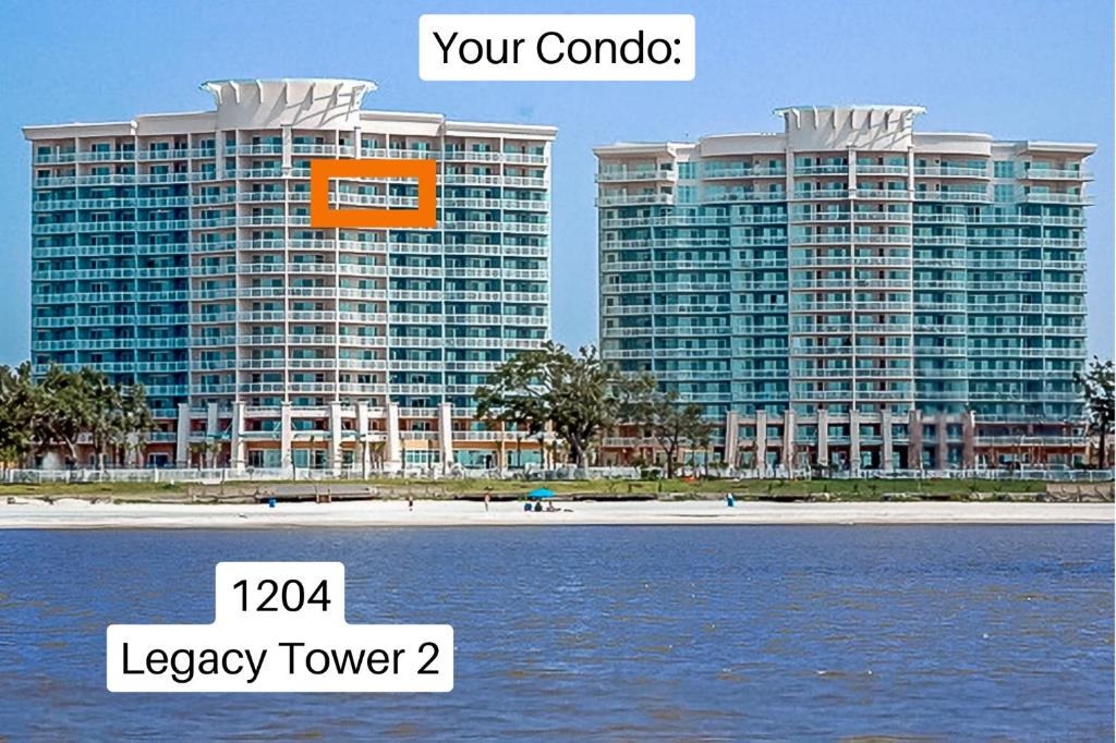 Ein großes Gebäude mit einem orangefarbenen Schild daran, neben dem Wasser in der Unterkunft Beachview Condo at Legacy Tower 2 -1204 - fully furnished 2 bedroom 2 bath in De Buys