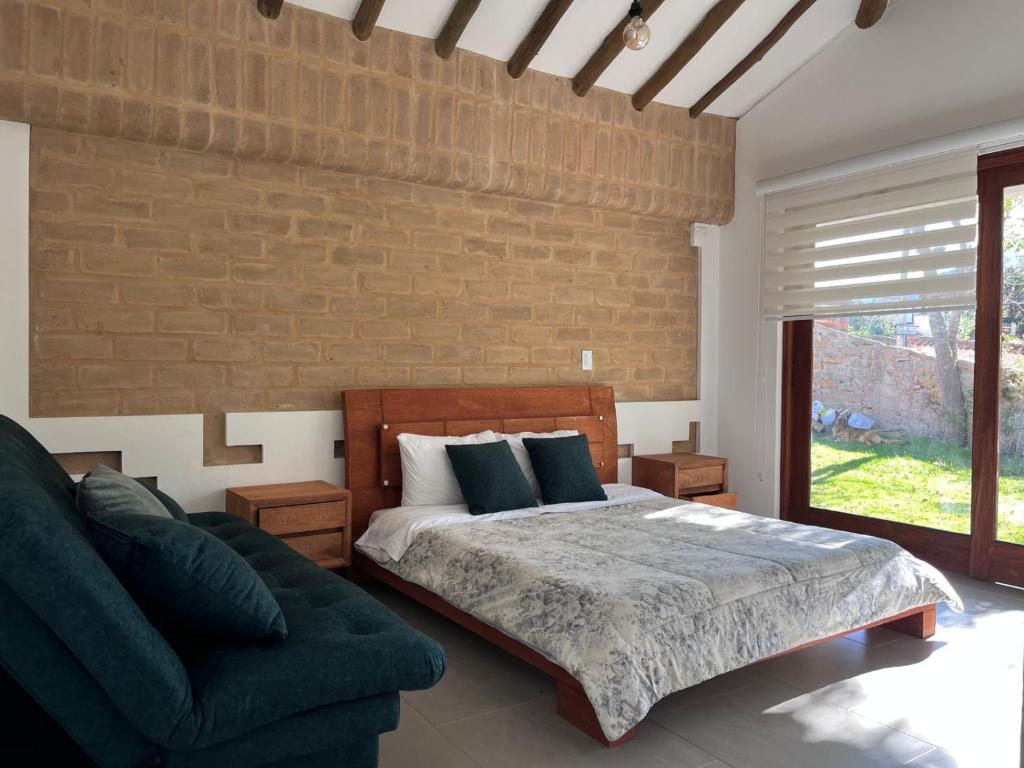 um quarto com uma cama, um sofá e uma parede de tijolos em refugio natal1 em Villa de Leyva
