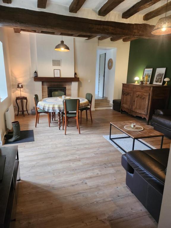 a living room with a table and chairs and a fireplace at Gite de campagne in Restigné