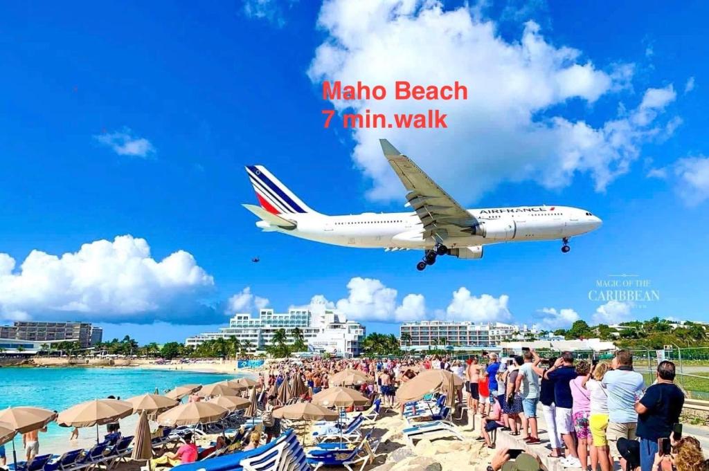 an airplane flying over a beach with a crowd of people at Maho Escape- with Pool and Gym, Lagoon view, walk to Maho Beach and Mullet Bay, walk to dinning in Maho Reef