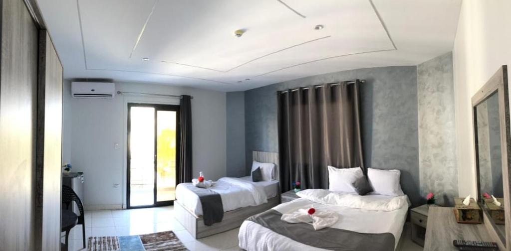 カイロにあるGarden city hotel Nile houseの白いシーツが敷かれたベッドが2つある寝室