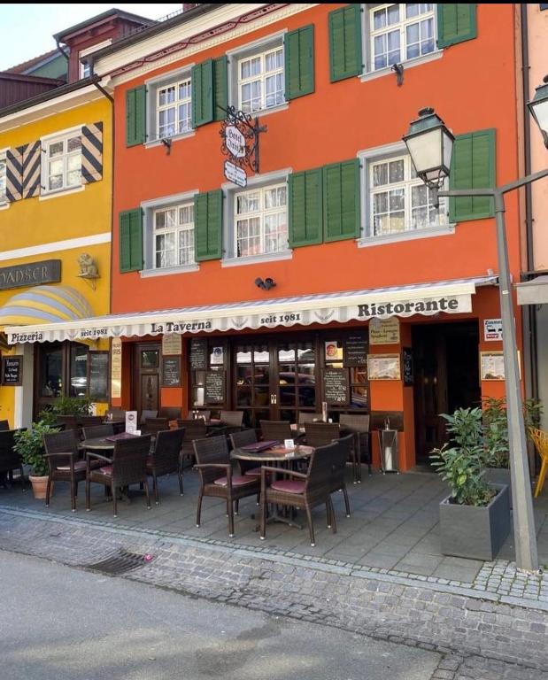 a restaurant with tables and chairs in front of a building at Hotel Iris- Pizzeria Ristorante La Taverna in Meersburg