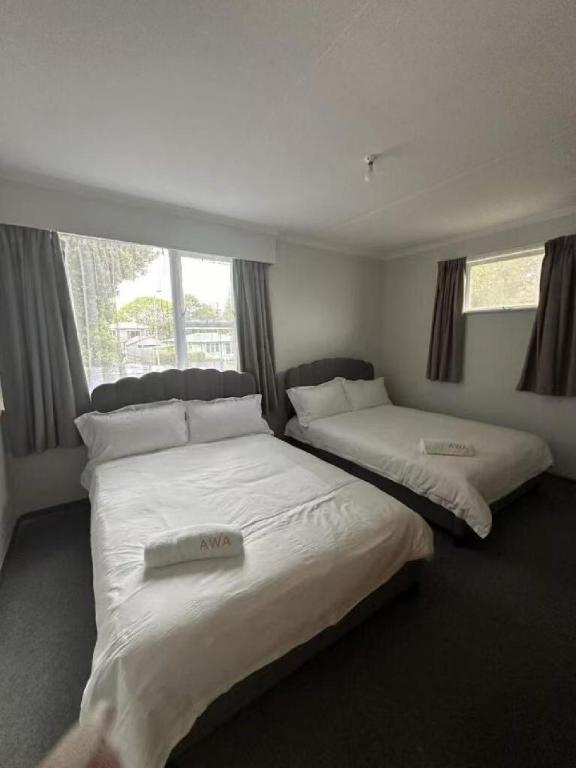 two beds in a room with two windows at 3 bedrooms House,77 Slacks Rd in Palmerston North