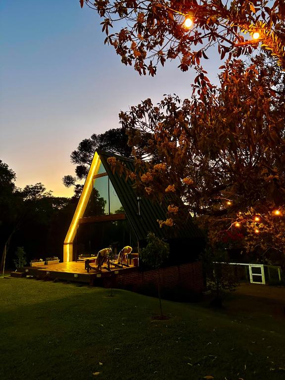 a house with a lit up facade in a yard at Cabana Pehuen in Santa Maria do Erval