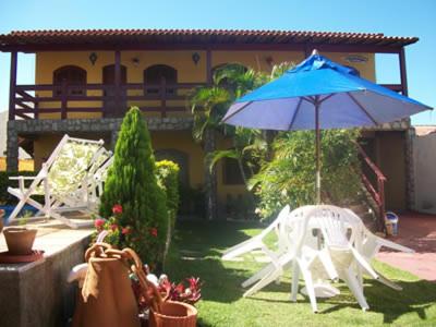 卡波布里奥Pousada Da Restinga的院子里的蓝色雨伞和白色椅子