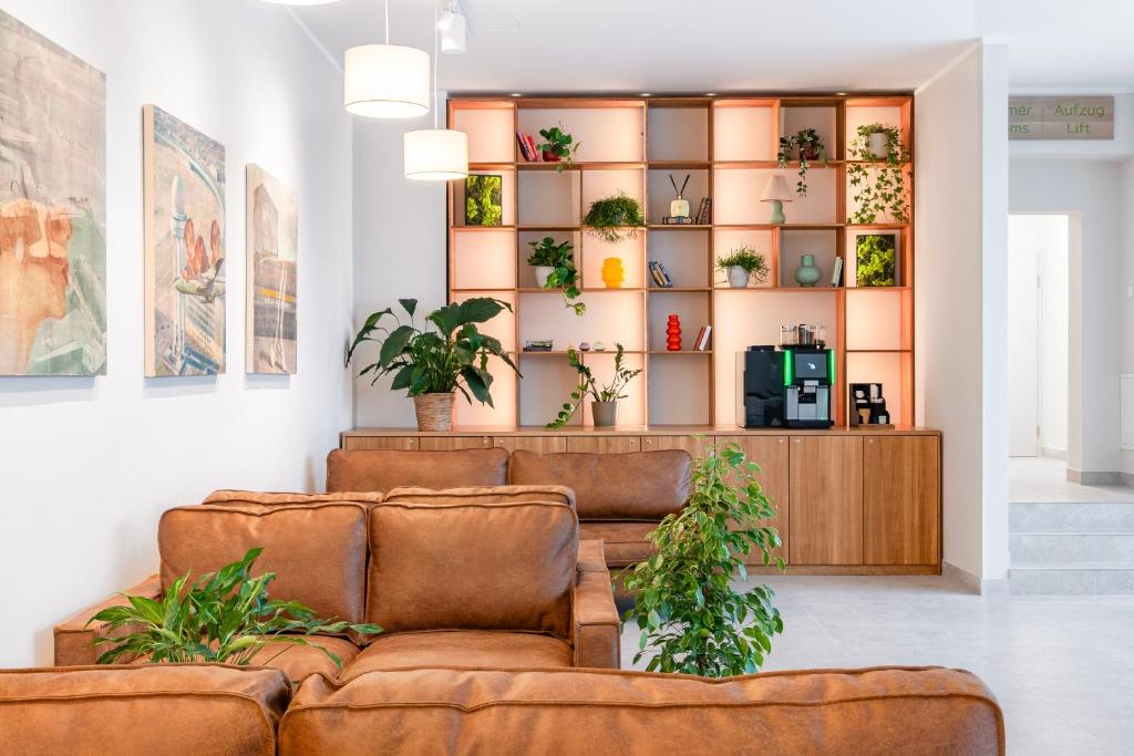 a living room with two brown couches and plants at Hotel Columbia Berlin am Platz der Luftbrücke in Berlin