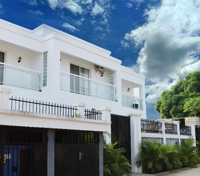 a white house with a gate and a fence at La Villa Grenade in Pointe-Noire