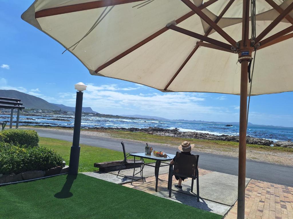 a person sitting at a table under an umbrella at Tide's Edge in Gansbaai