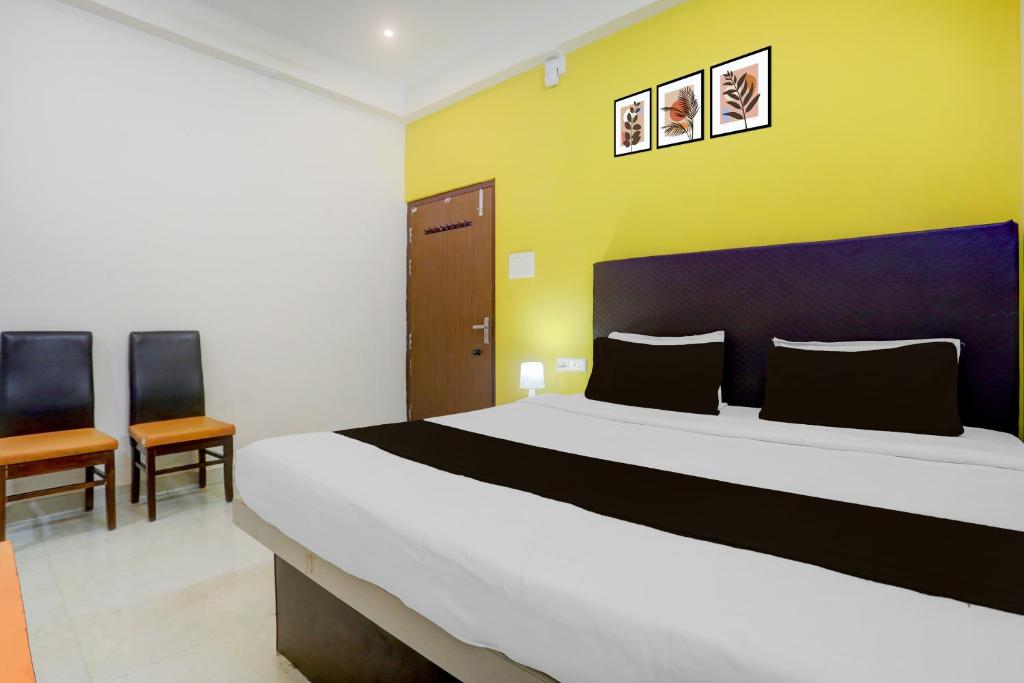 a bedroom with a large bed and two chairs at HOTEL O AADRITI RESIDENCY in Bhubaneshwar