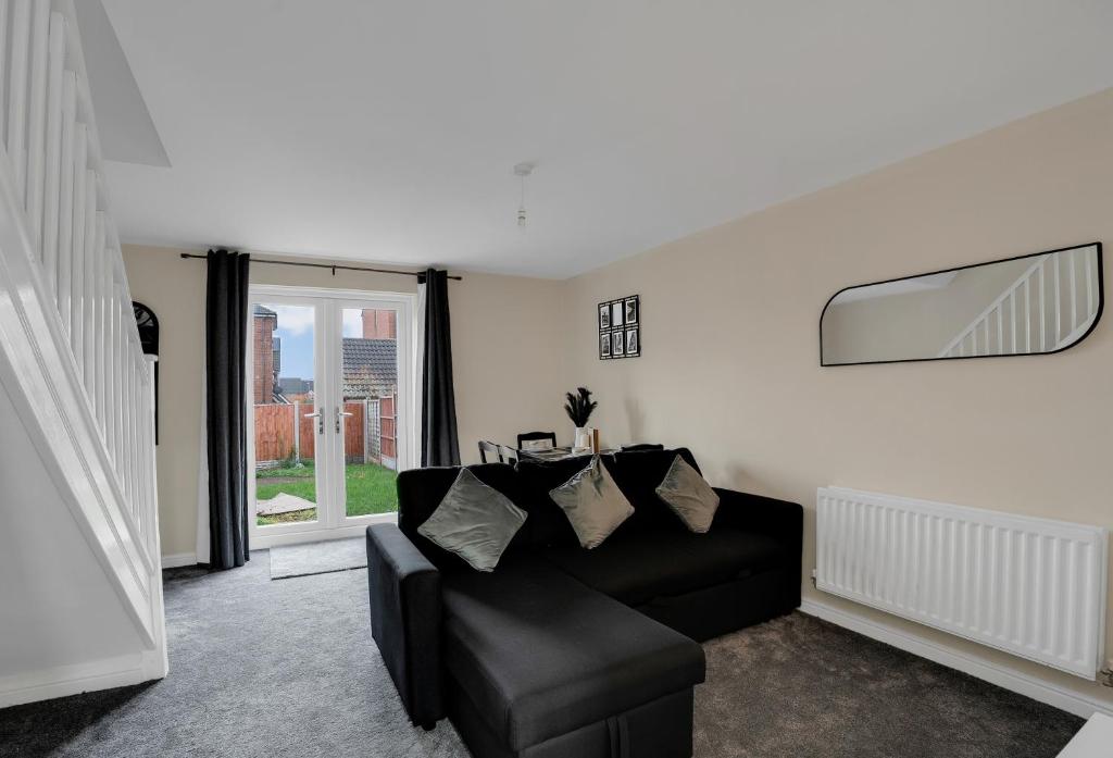 ein Wohnzimmer mit einem schwarzen Sofa und einem Fenster in der Unterkunft Luxury 2-Bedroom Home 10 Minutes from Birmingham City Centre in Birmingham