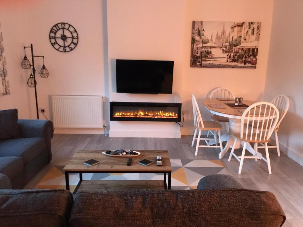 a living room with a couch and a table and a fireplace at Stunning modern apartment in the Cotswolds 55 minute drive to Bath Christmas market in Chalford