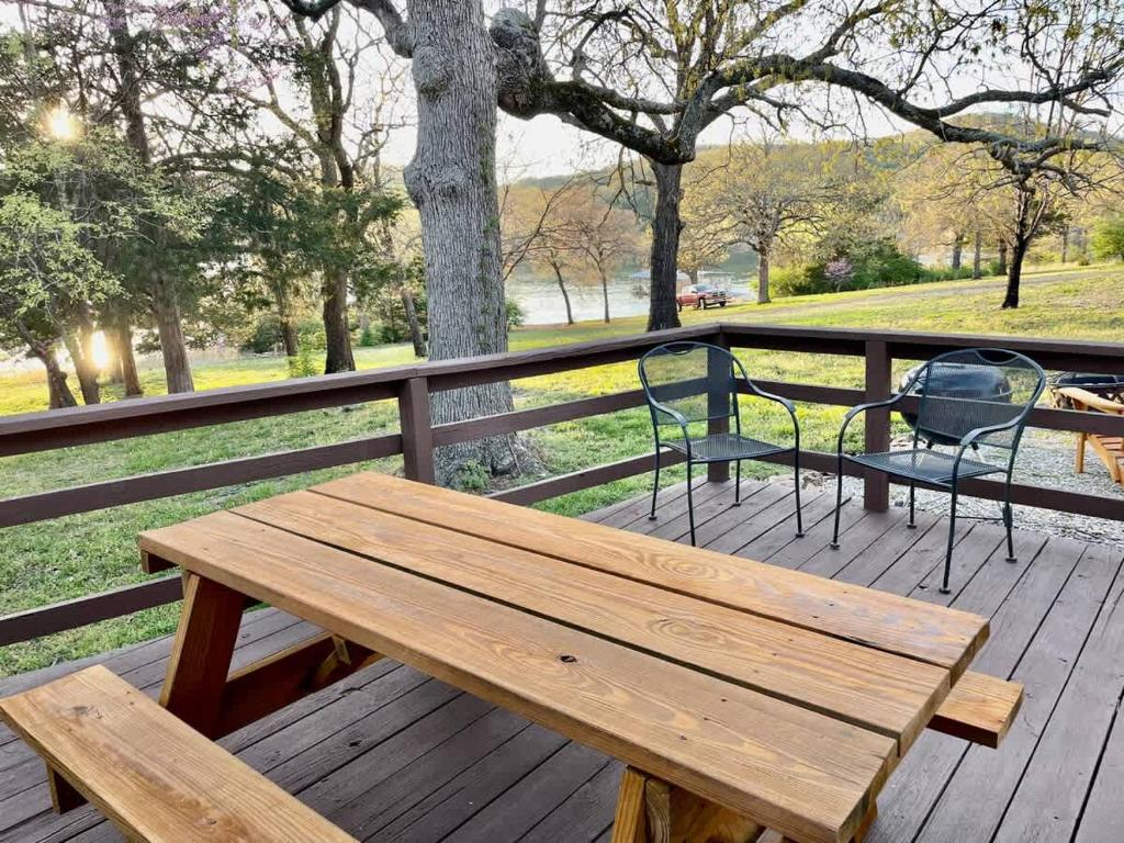 a wooden picnic table and a chair on a deck at Cozy Cottage - Lakeview in Reeds Spring