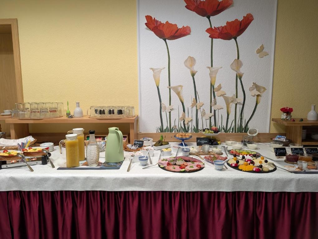 a table with plates of food and flowers on it at Pension zum Reiterhof, 3-Bettzimmer in Schmogrow