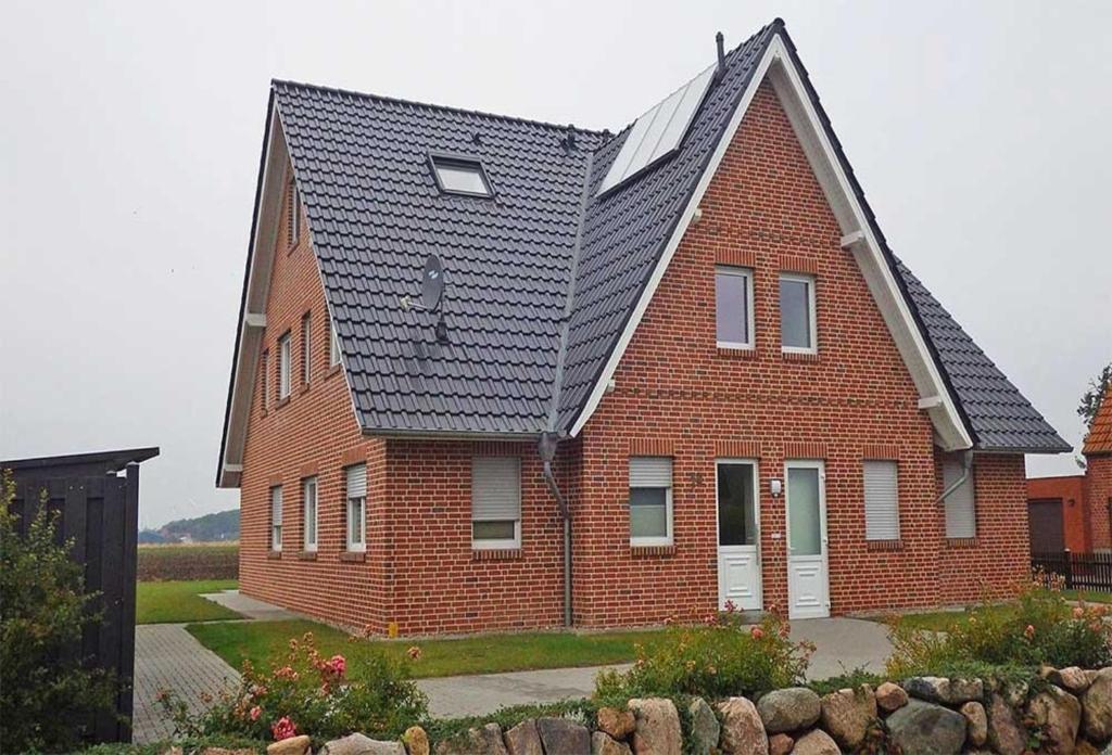 une grande maison en briques avec un toit en gambrel dans l'établissement Meerestraum, à Neue Tiefe Fehmarn