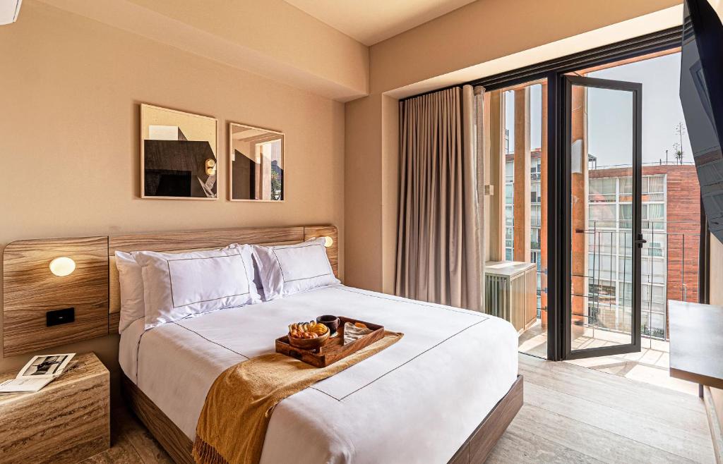 a bedroom with a bed with a tray of food on it at Kukun Edition Marsella Juarez in Mexico City