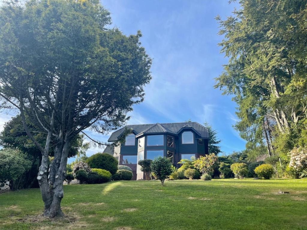 a house on a lawn with a tree at Beautiful Plot Lake and Volcano View in Puerto Varas