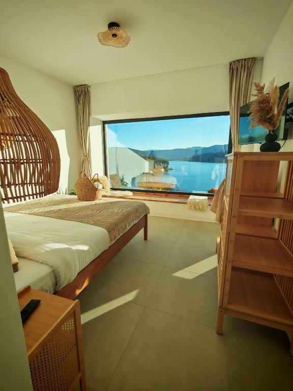 a bedroom with a large window with a view of the ocean at Moon Lake Bicaz - Aurora Garden in Buhalniţa