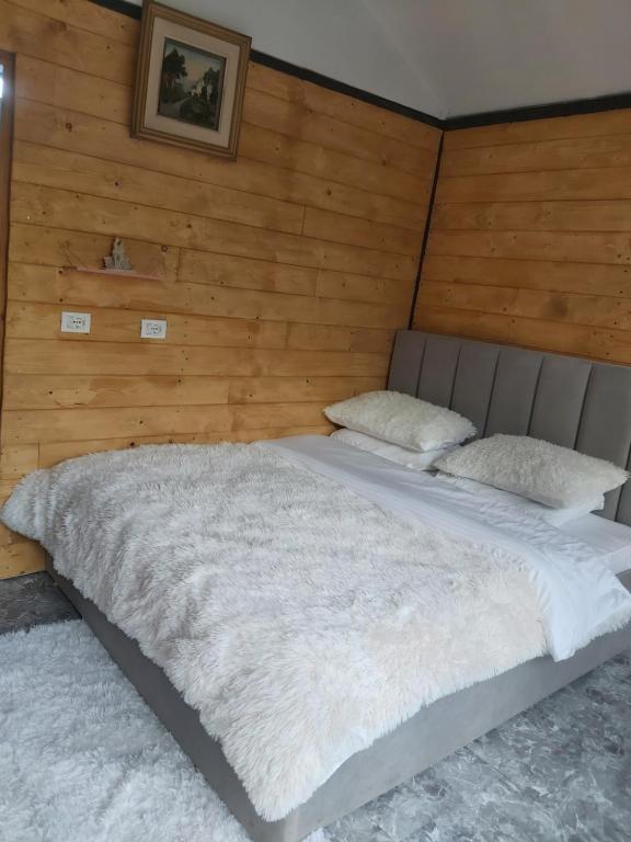 a bed in a room with a wooden wall at Boga Cabins in Bogë