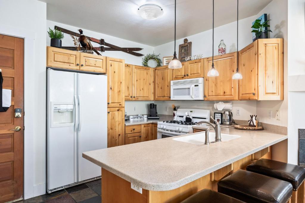 a kitchen with wooden cabinets and a white refrigerator at Summit Sanctuary, Sleeps 4, Charming Interiors, 20 Minutes from the Mountain! in Gorgosa