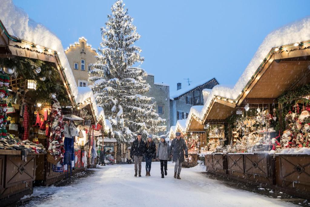 Un grupo de personas caminando por una calle nevada con un árbol de Navidad en T-Collection Premium Apartments, en Vipiteno