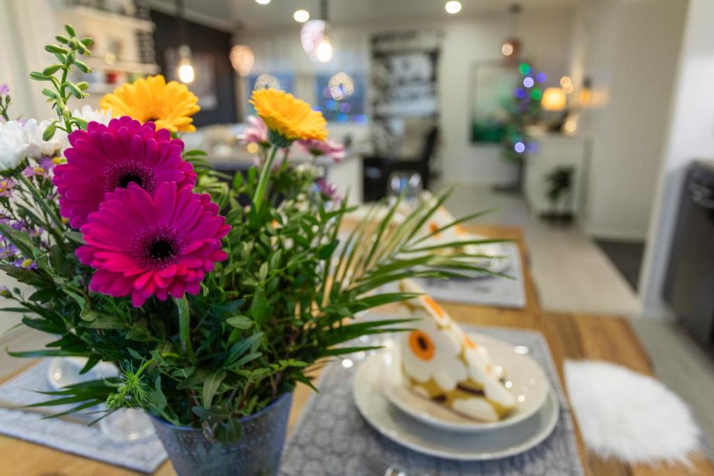 un vase de fleurs sur une table avec une assiette de nourriture dans l'établissement Vasko Luxurious Suites, Firefox, à Rovaniemi