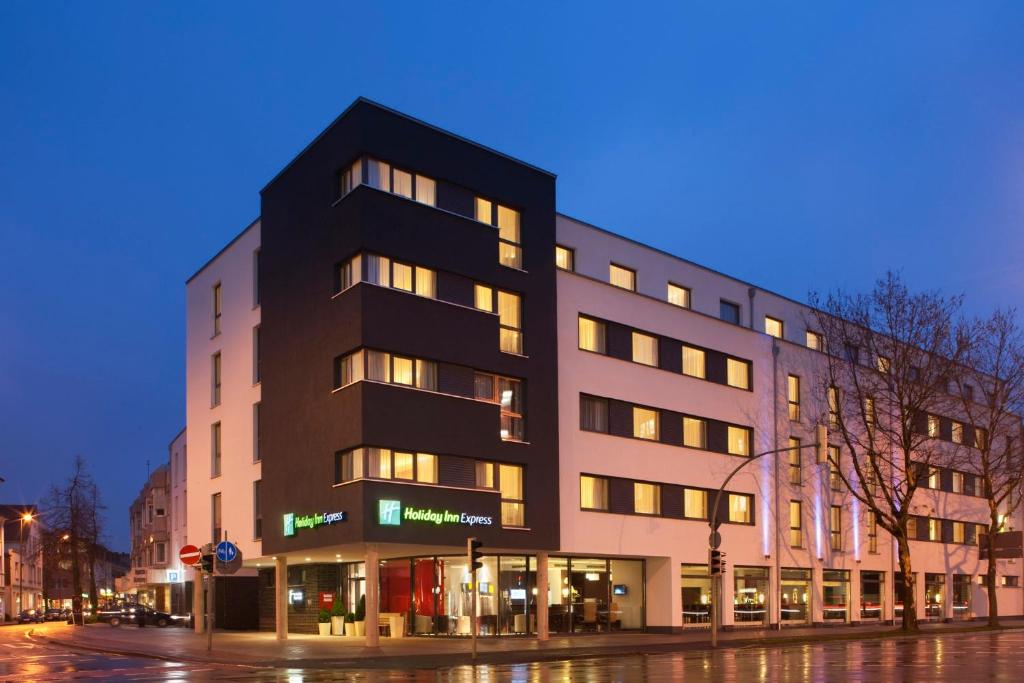 a large building on a city street at night at Holiday Inn Express Gütersloh by IHG in Gütersloh