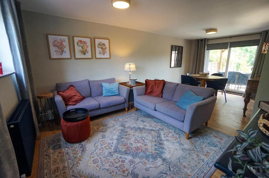a living room with two blue couches and a rug at Beautiful 2 Bed Home with Spacious Garden in Shephall