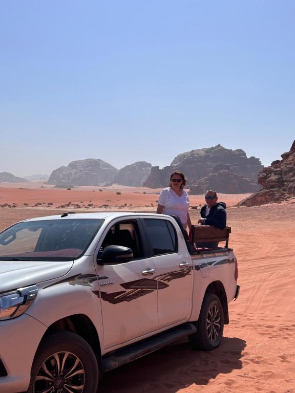 two people sitting in the back of a truck in the desert at Desert Life Camp Wadi Rum in Wadi Rum