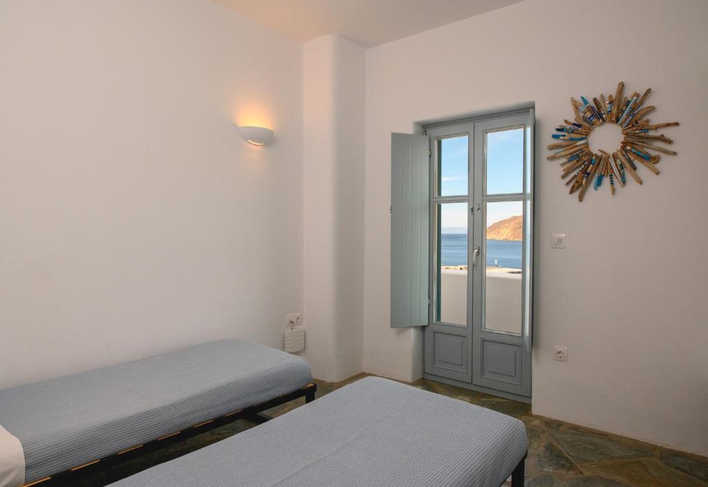 a room with two beds and a door with a window at Amorgos Elegant Houses, Villa 3 in Aegiali